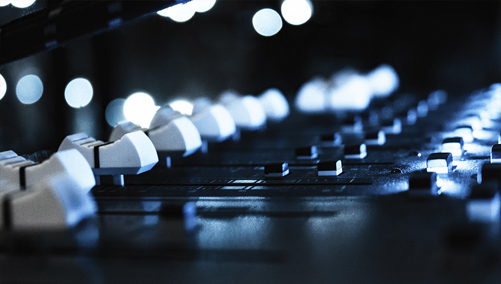Fotografía de los fadders de la mesa de sonido con un efecto de luces