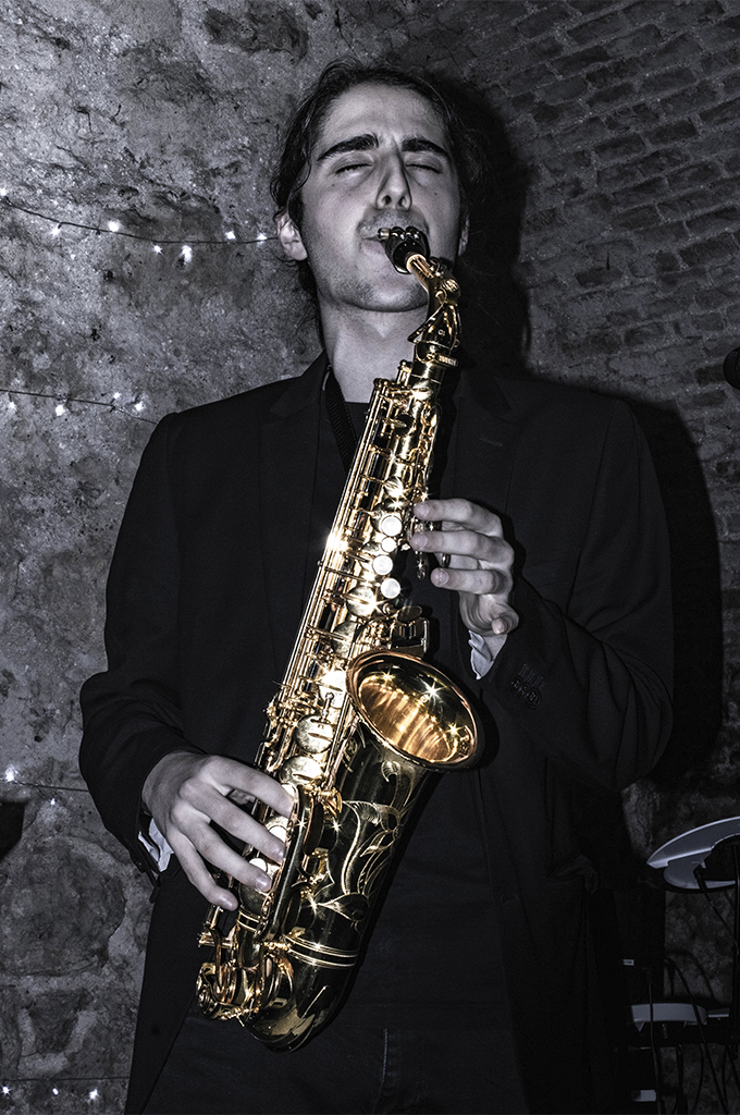 Fotografía en blanco y negro del saxofonista dando importancia a su instrumento