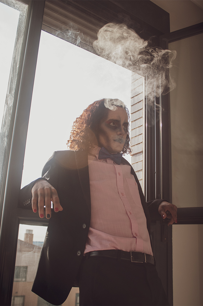 Fotografía de retrato de un chico maquillado en una ventana